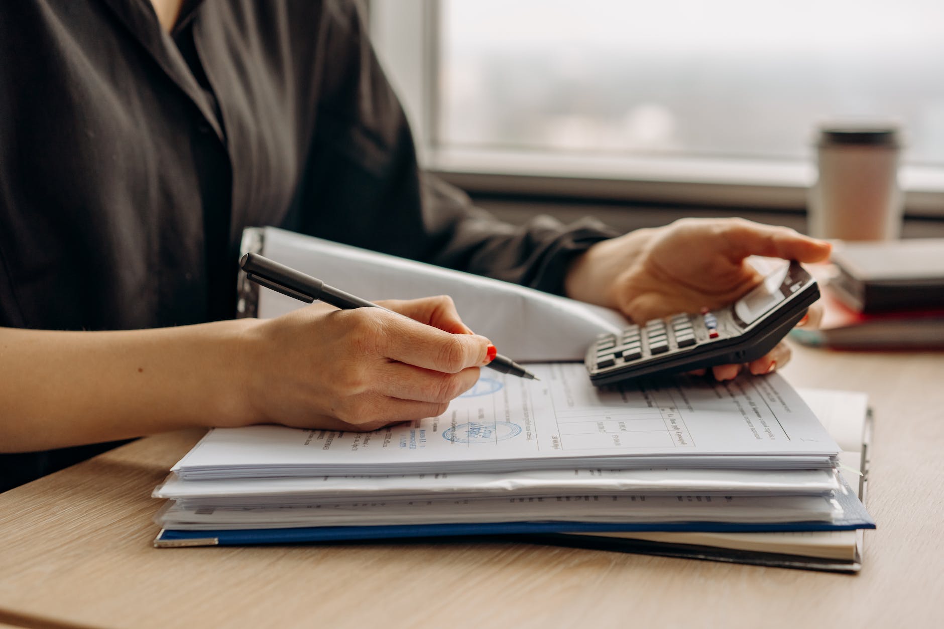 person in long sleeve shirt holding a calculator doing retail accounting