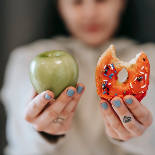 woman showing apple and bitten doughnut