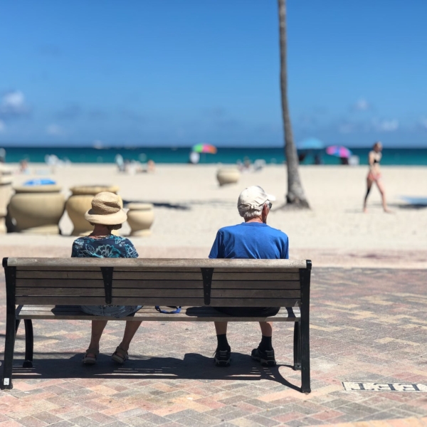 man and woman sitting on brown wooden bench