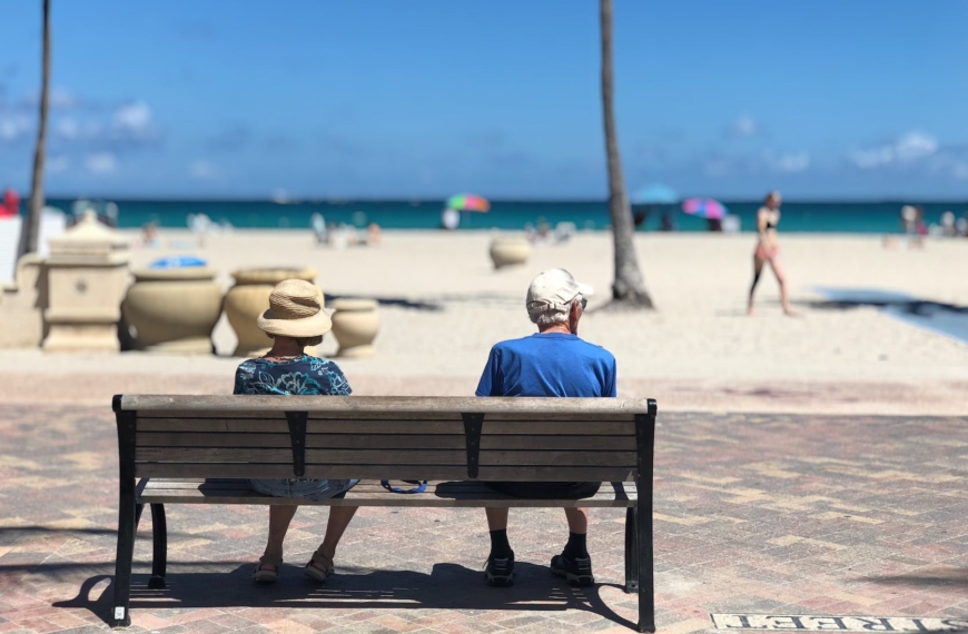 man and woman sitting on brown wooden bench