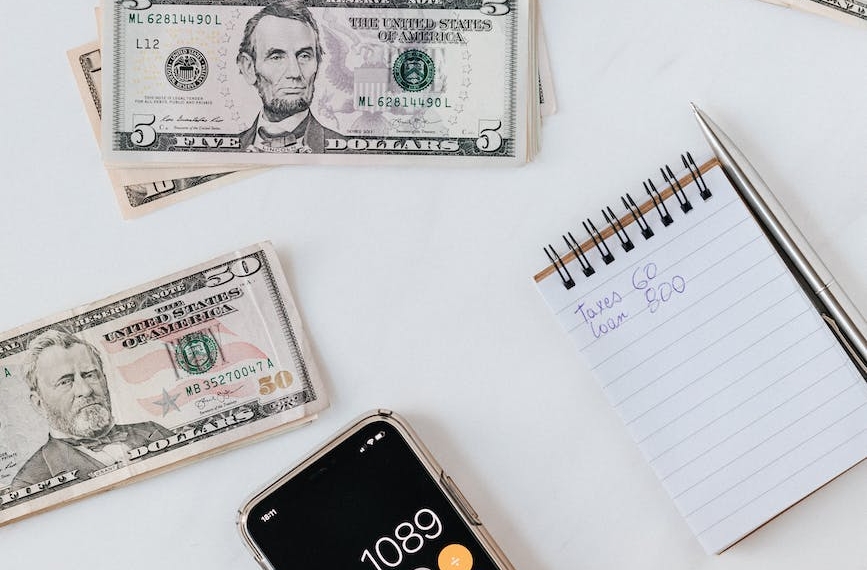 crop anonymous person calculating profit on smartphone calculator near banknotes