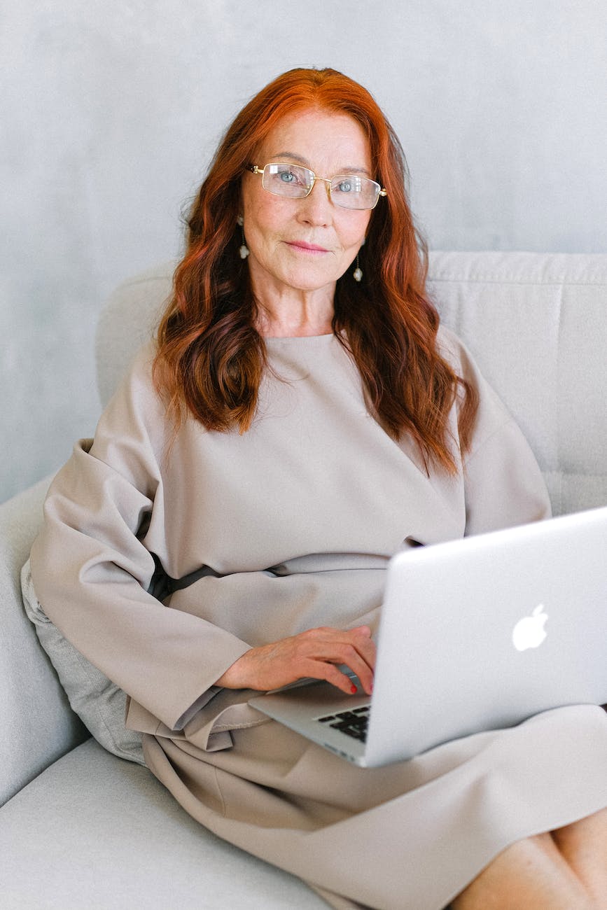 charming elderly woman using laptop on sofa