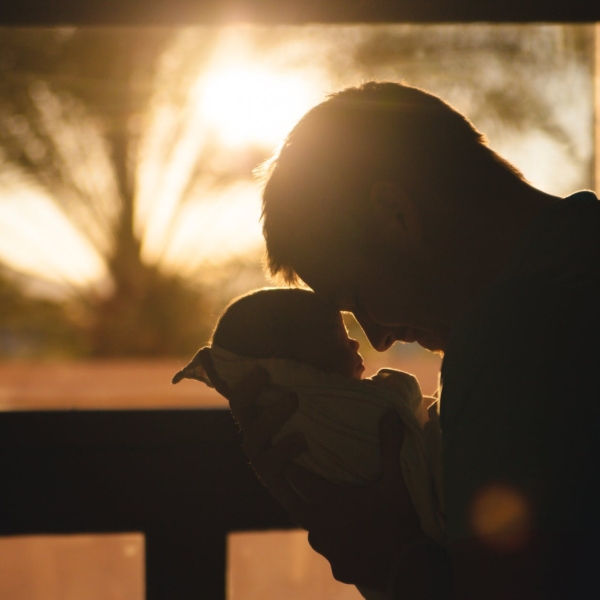 man carrying baby drawing their foreheads