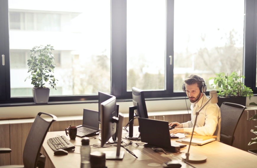 man with headphones facing computer monitor