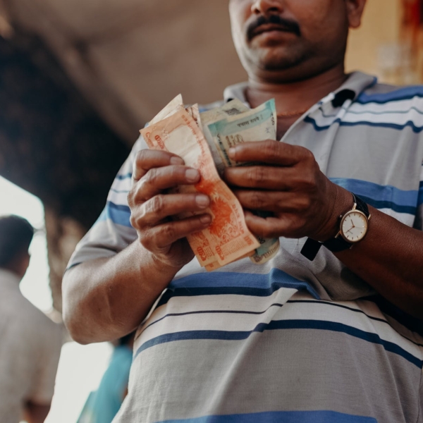 man in blue and white stripe polo shirt holding banknote