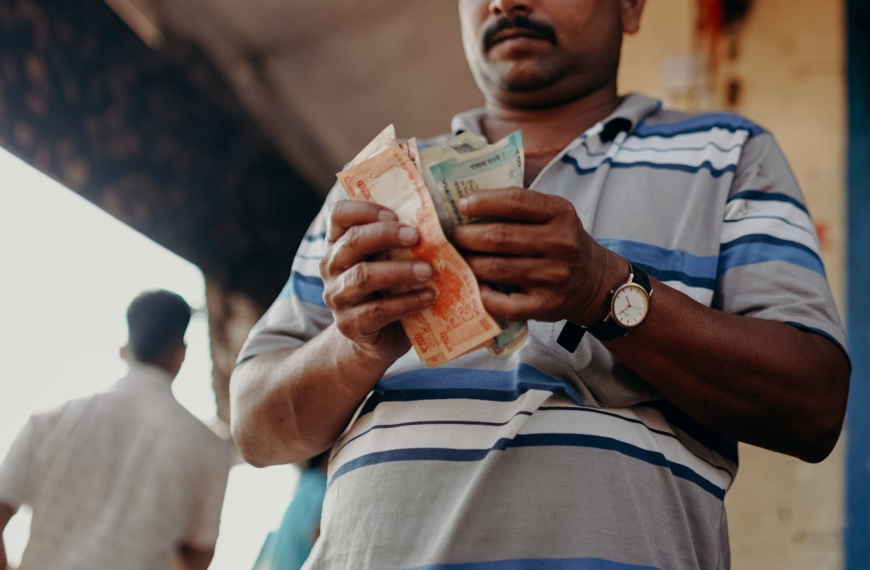 man in blue and white stripe polo shirt holding banknote