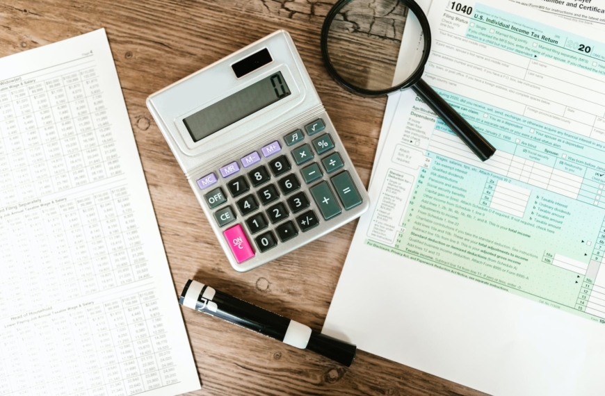gray calculator and black magnifying glass on brown wooden surface