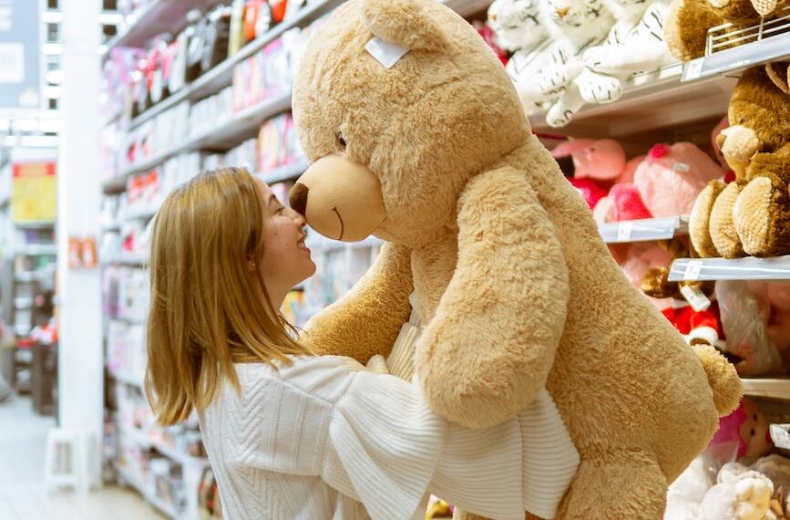 woman carrying bear plush toy inside store