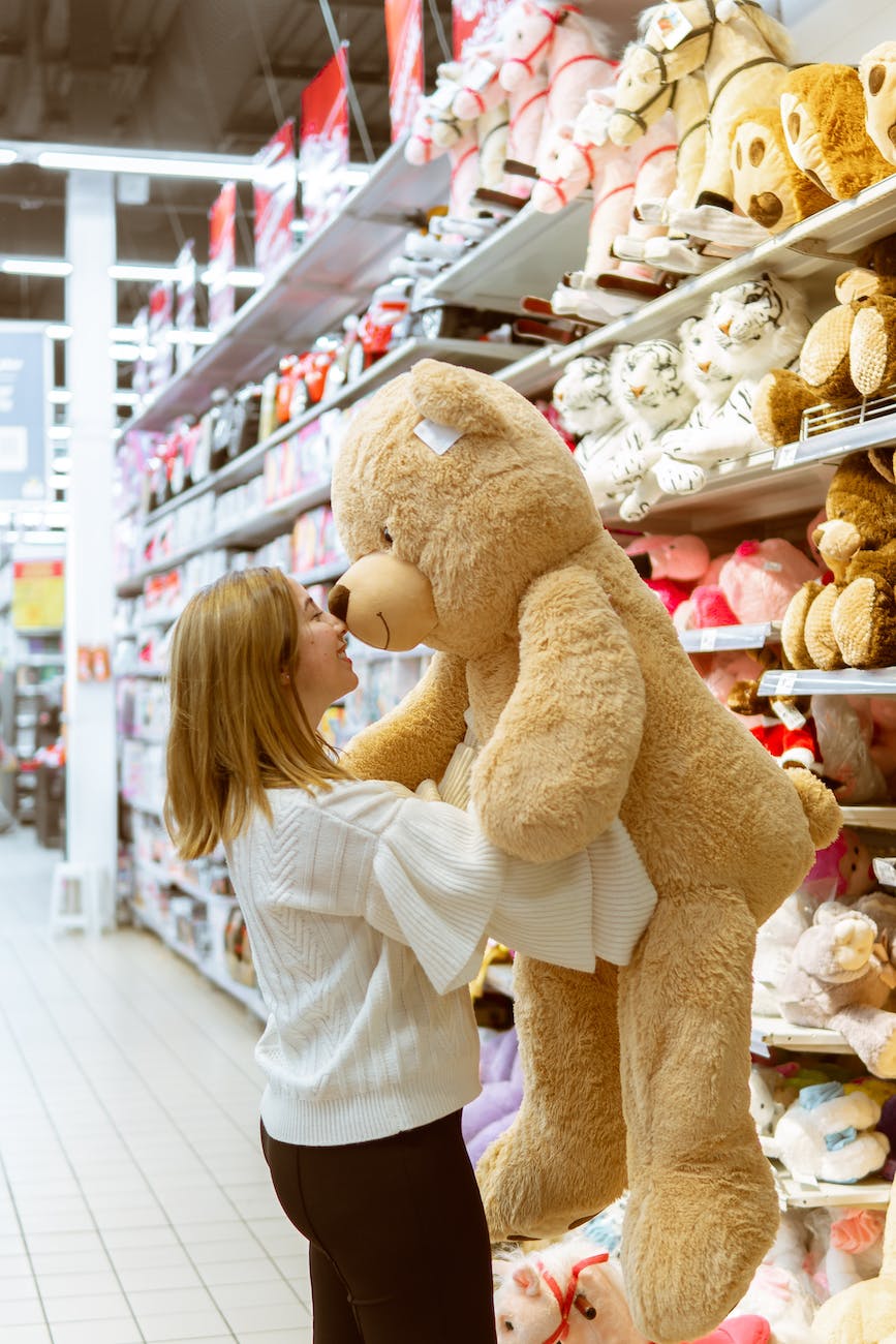 woman carrying bear plush toy inside store