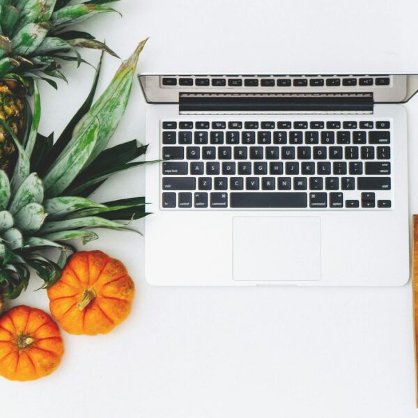white macbook near pineapple and pumpkin