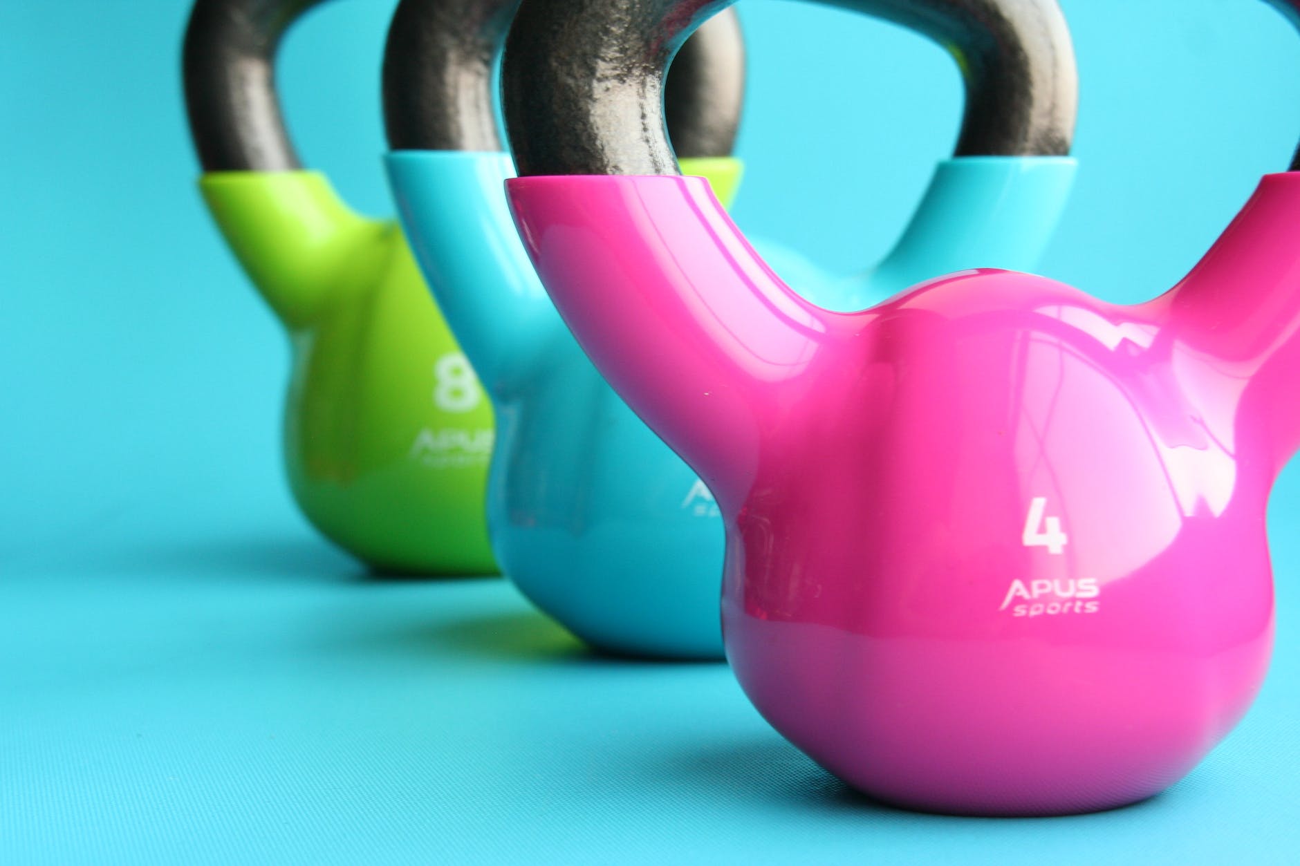 green blue and pink kettle bells on blue surface