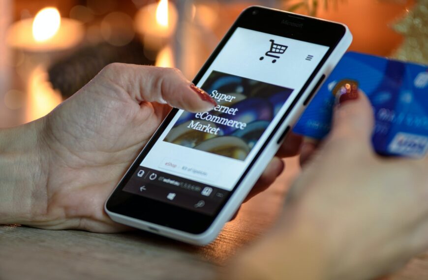 person using black and white smartphone and holding blue card