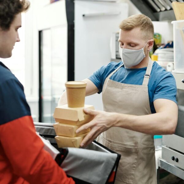 man wearing a face mask putting food on a thermal bag