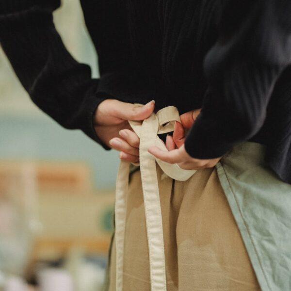 crop faceless woman tying up apron laces