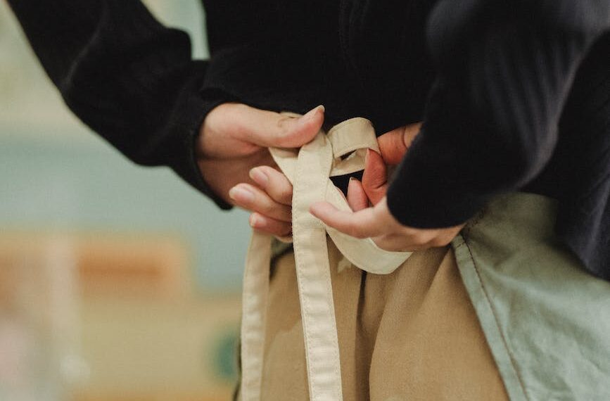 crop faceless woman tying up apron laces