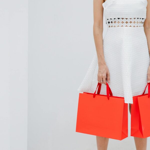 crop unrecognizable woman carrying red shopping bags in studio