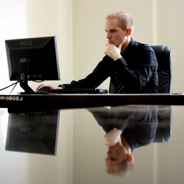 man sitting facing pc inside room