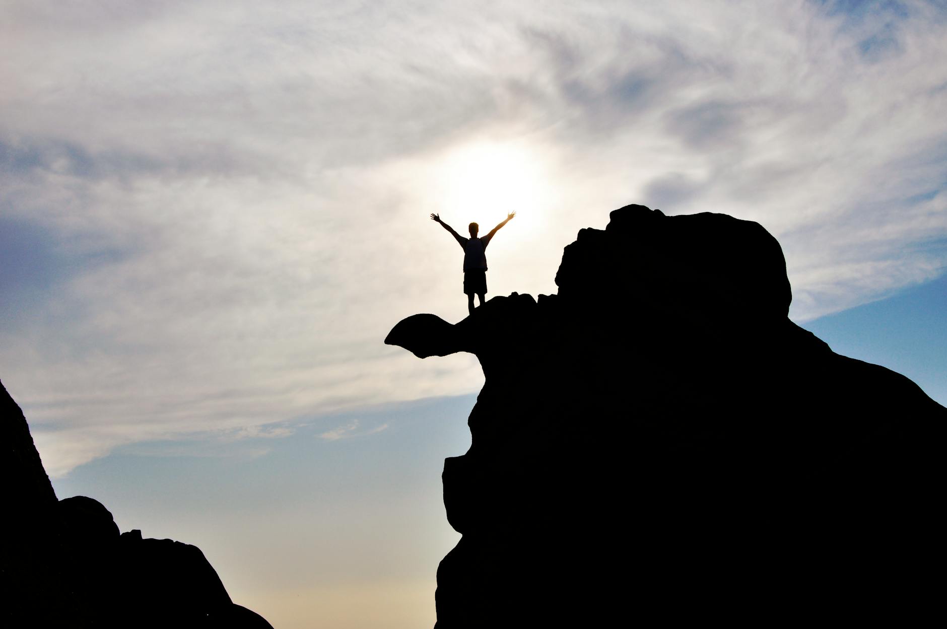 silhouette photography of person standing on rock