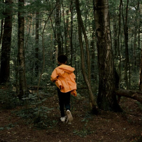 rear view of teenage boy running in forest