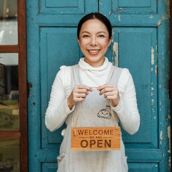 ethnic female cafe owner showing welcome we are open inscription