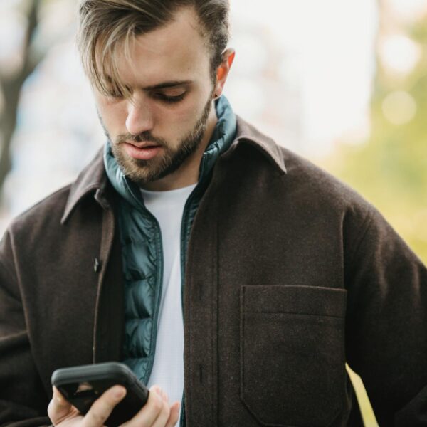 young hipster looking at smartphone screen in park