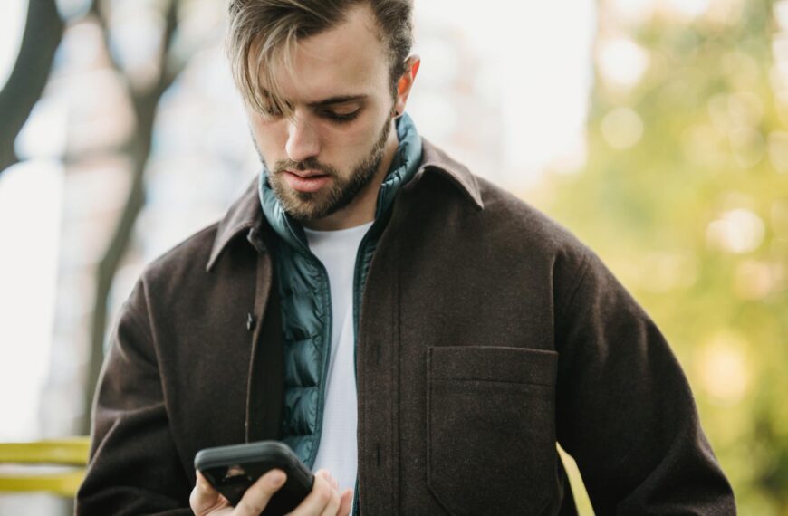 young hipster looking at smartphone screen in park