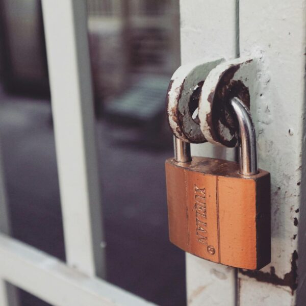 closeup photography of white gate with brass colored padlock