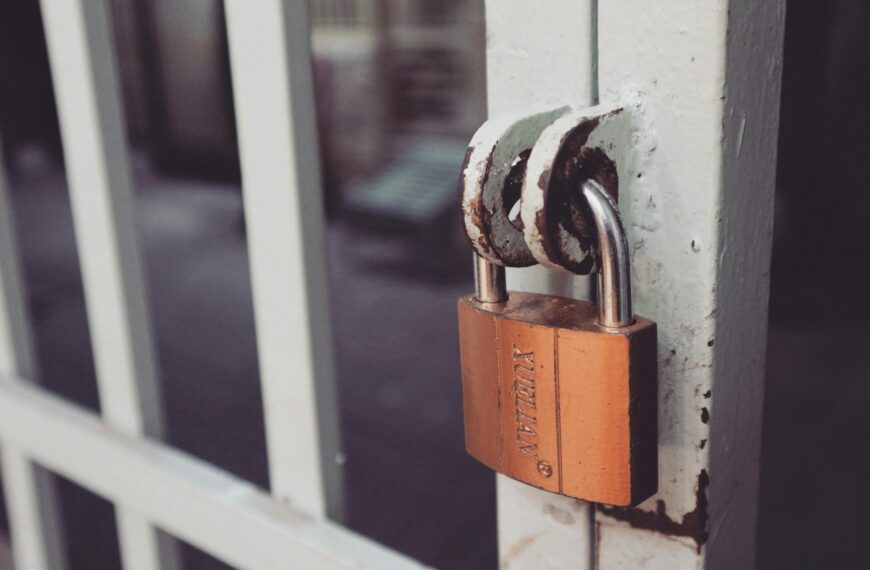 closeup photography of white gate with brass colored padlock